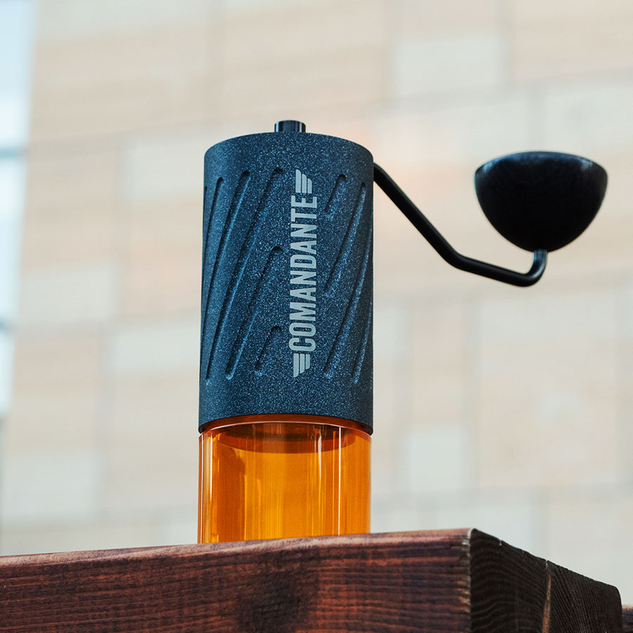 Comandante C60 Baracuda Nautilus Blue – Nahaufnahme mit Kurbel und Auffangbehälter auf Holzbalken – Coffee Coaching Club