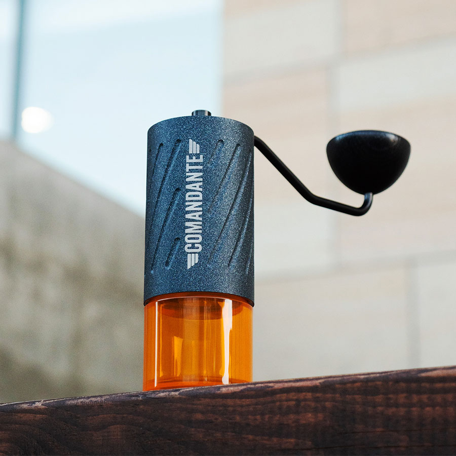 Comandante C60 Baracuda Nautilus Blue – Handmühle auf Holzbalken vor Natursteinfassade – Coffee Coaching Club