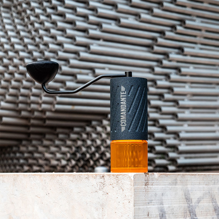 Comandante C60 Baracuda Nautilus Blue – Handmühle auf Holzbalken vor Metallrohr-Fassade – Coffee Coaching Club