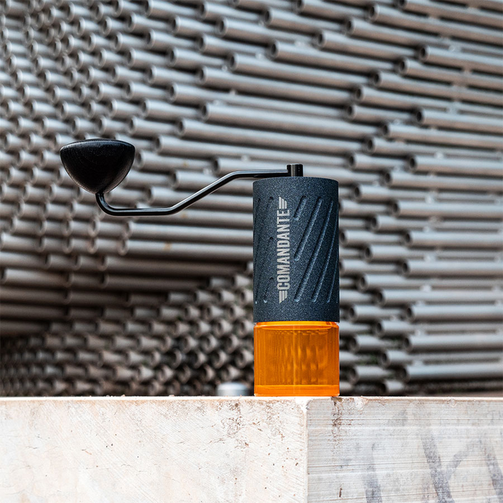 Comandante C60 Baracuda Nautilus Blue – Handmühle auf Holzbalken vor Metallrohr-Fassade – Coffee Coaching Club