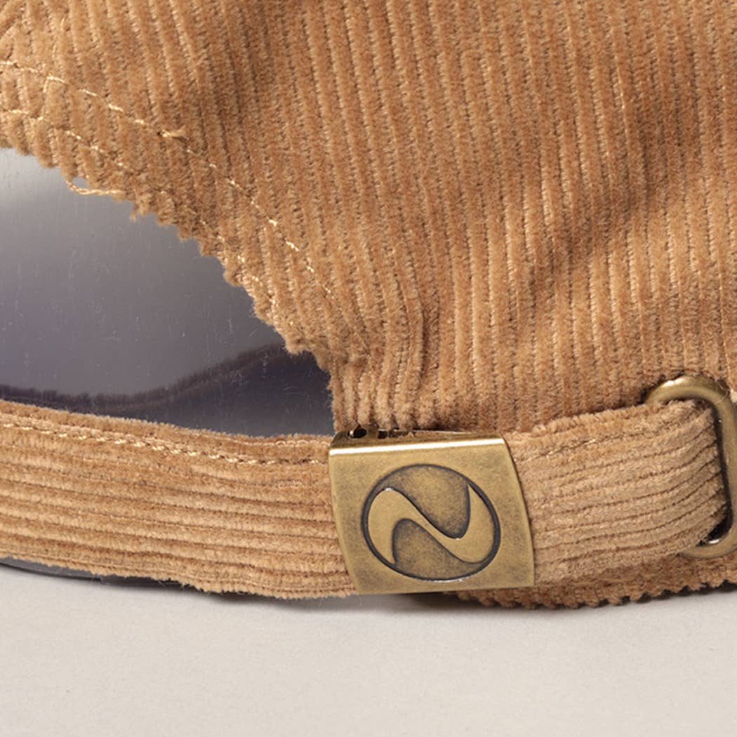 Close-up of the adjustable metal buckle closure on a tan corduroy cap