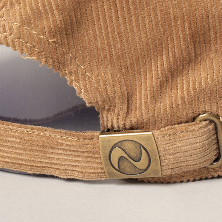 Close-up of the adjustable metal buckle closure on a tan corduroy cap
